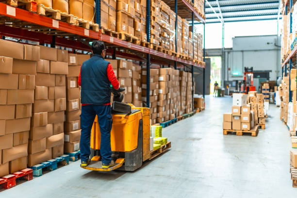 A man operates a forklift inside a warehouse, maneuvering through stacks of goods and equipment in a monthly storage unit in Hudson, FL.