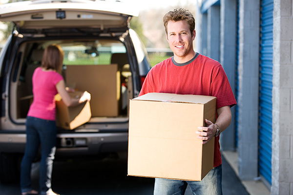 People moving boxes into a storage unit