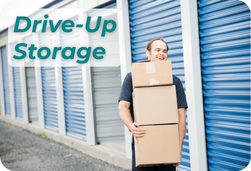 Image of a man carrying boxes in front of a drive-up storage facility
