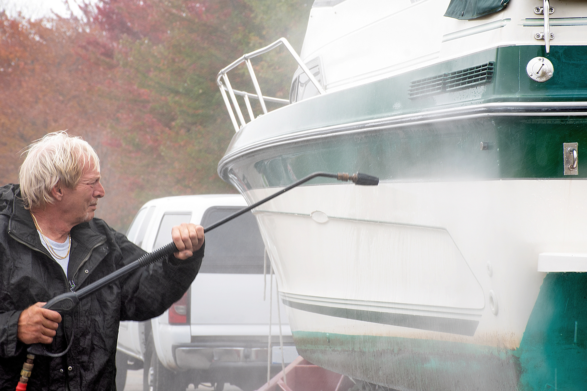 middle aged man powerwashing a jet boat on a trailer