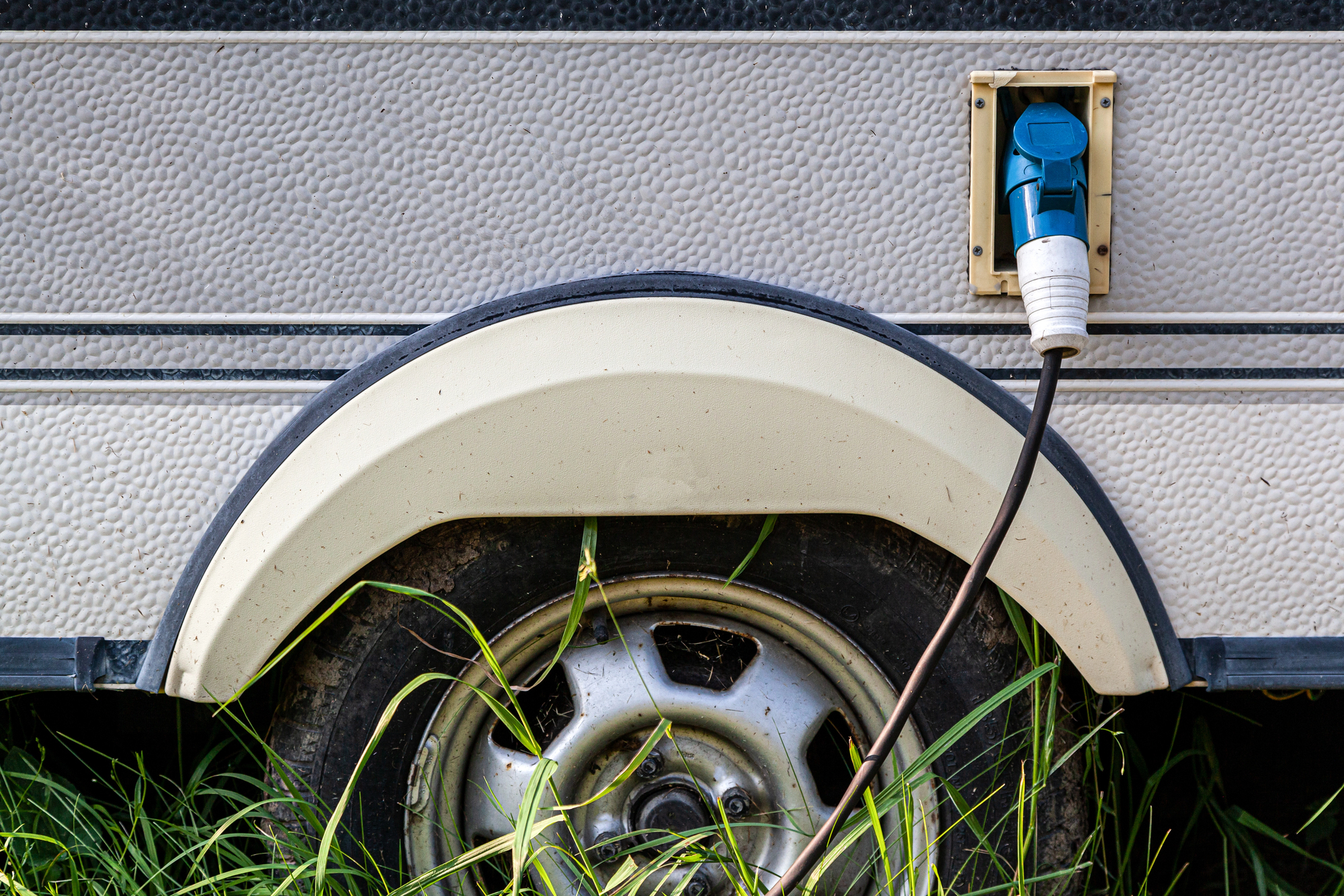 closeup of an RV and tire sinking into tall grass