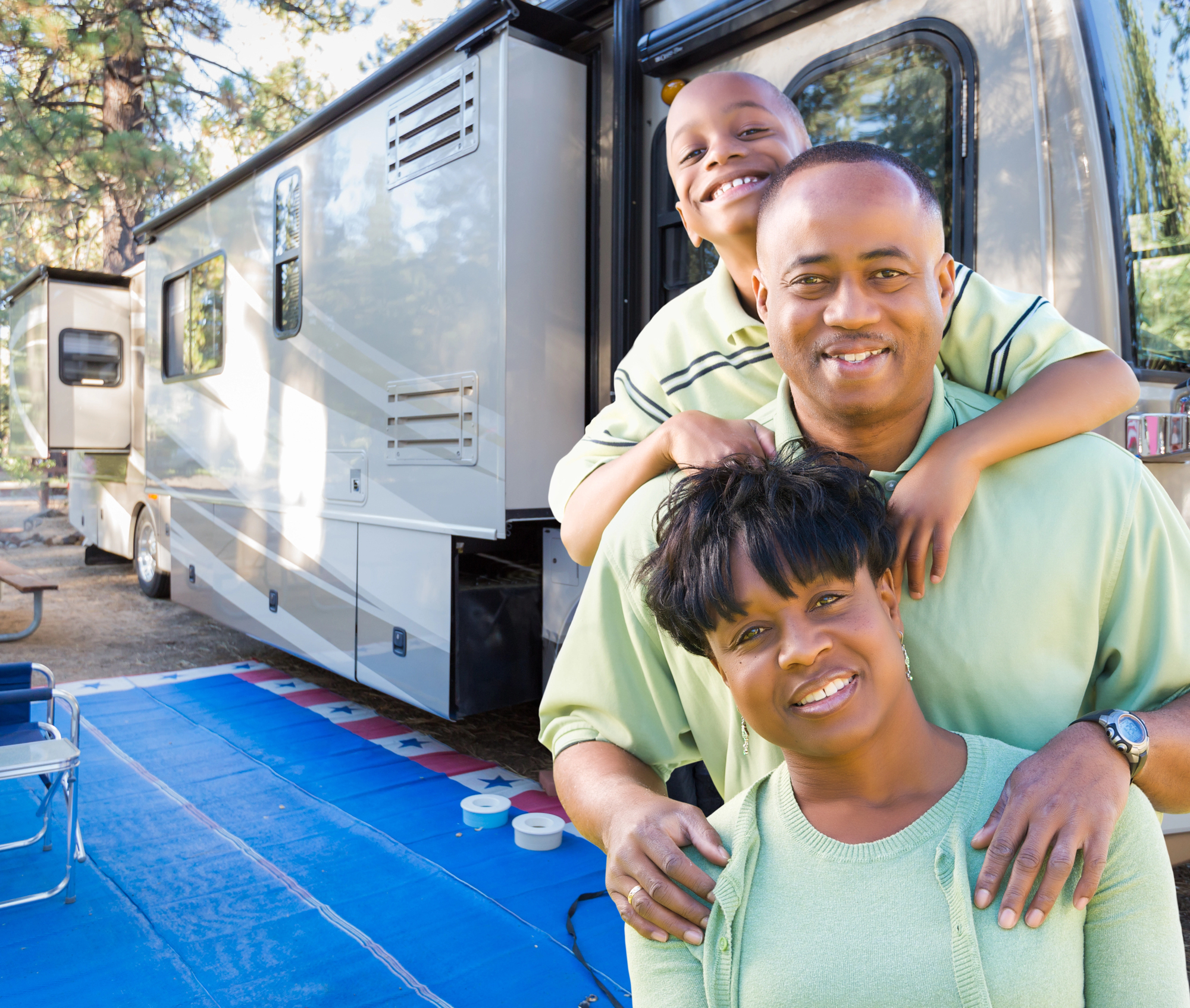Mom dad and son smiling in front of their RV Camper Mom dad and son smiling in front of their RV Camper