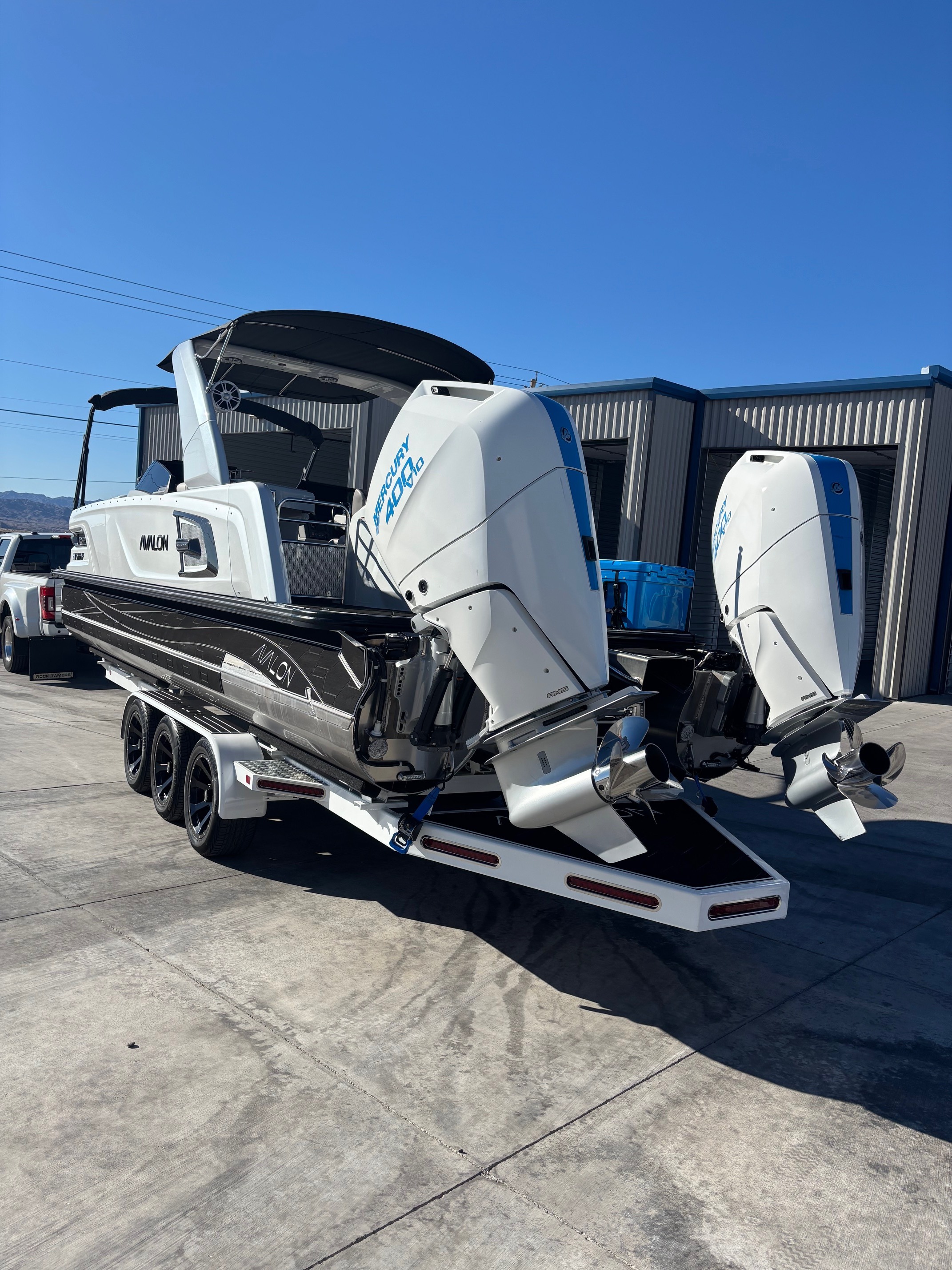 Rear view of a large high-performance luxury boat with twin motors parked on a wide concrete driveway at Showplace Storage.