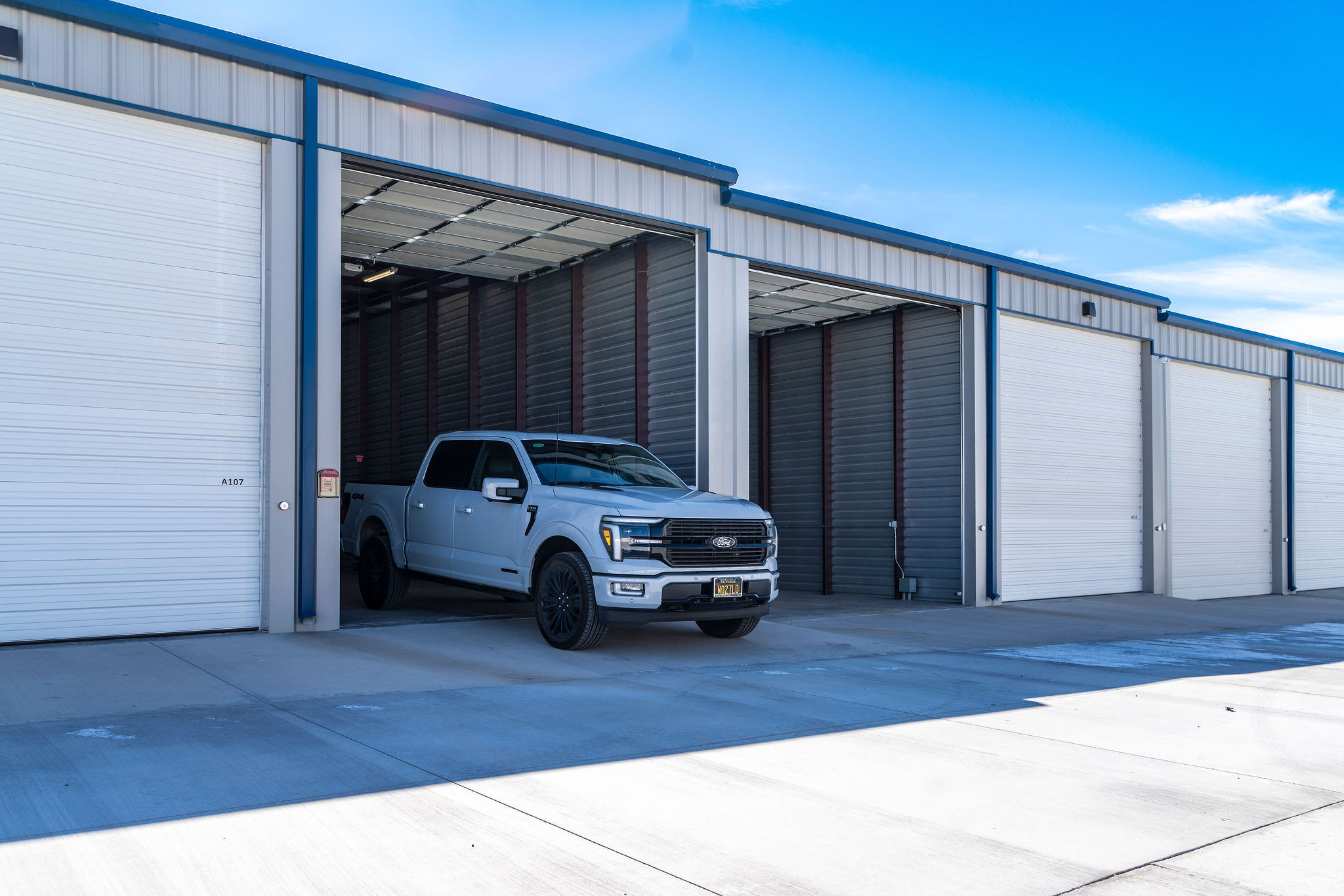 A white full-size pickup truck parked easily inside a spacious, extra-deep storage unit with tall roll-up doors in Lake Havasu.