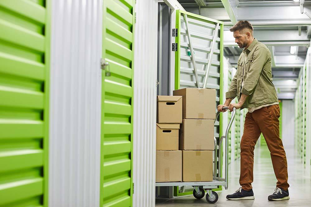 man pushing boxes into small storage unit man pushing boxes into small storage unit