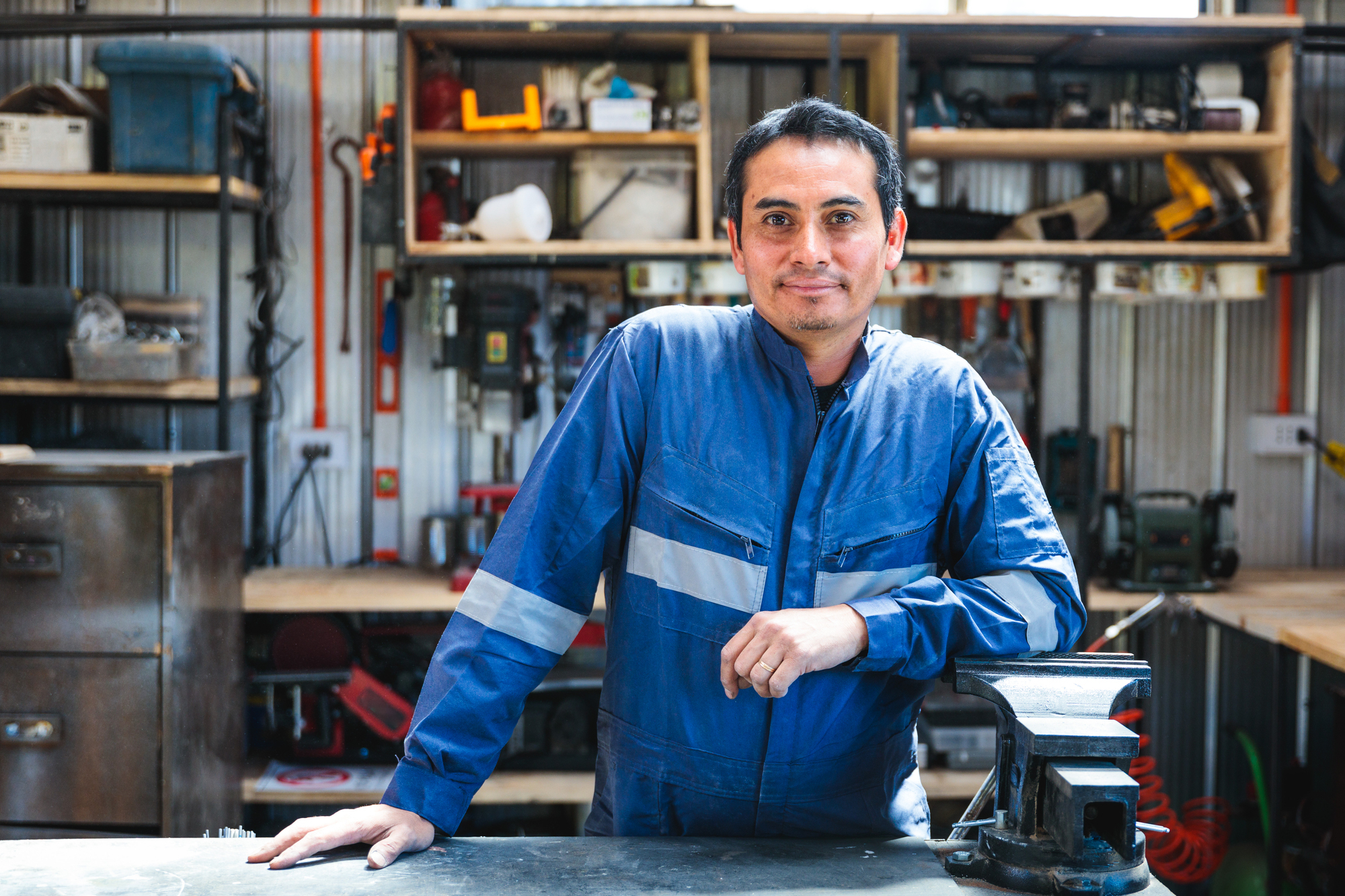 Small business owner standing at a workbench in a garage workshop Small business owner standing at a workbench in a garage workshop
