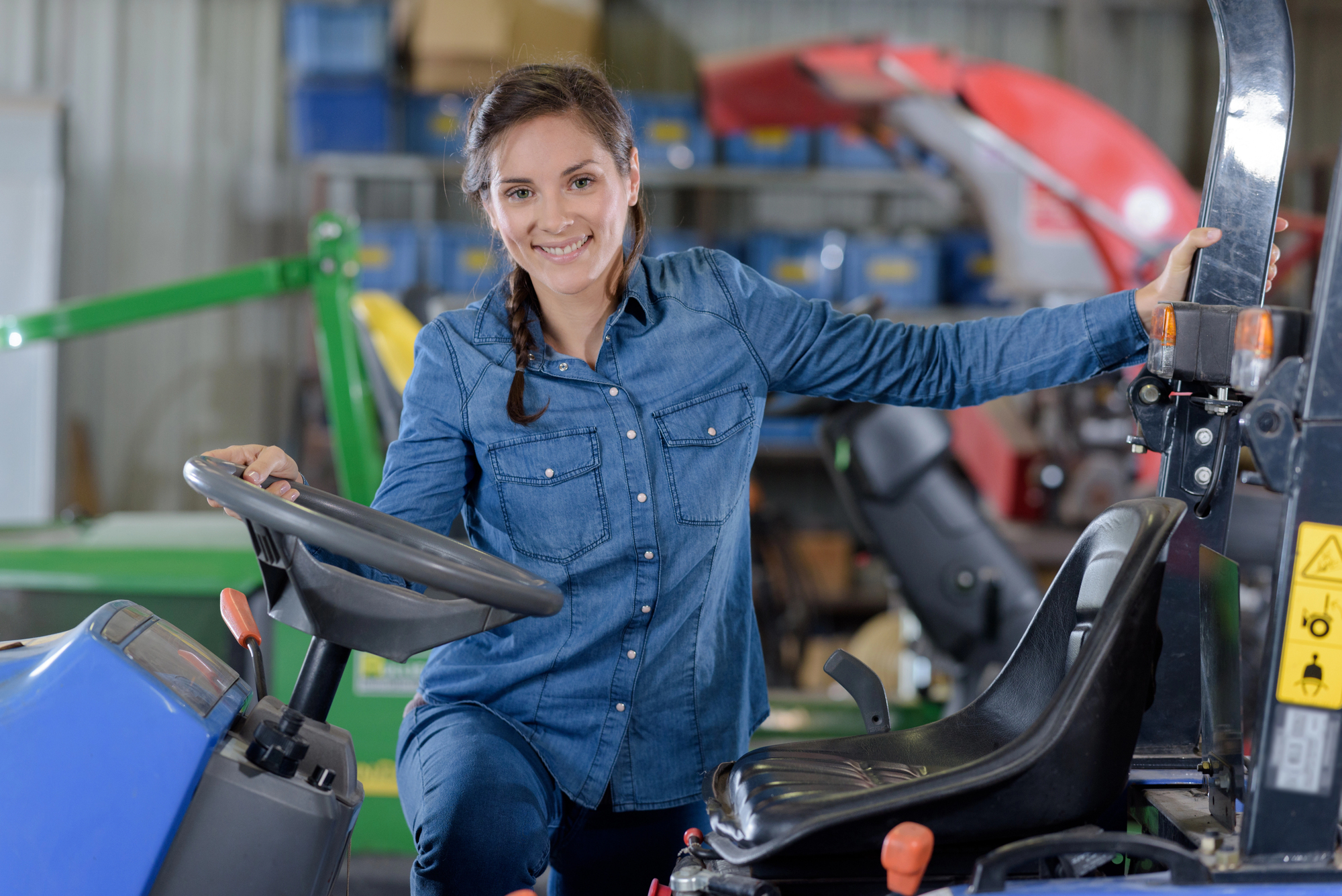 Female business owner smiling next to her commercial lawn mower in a equipment garage