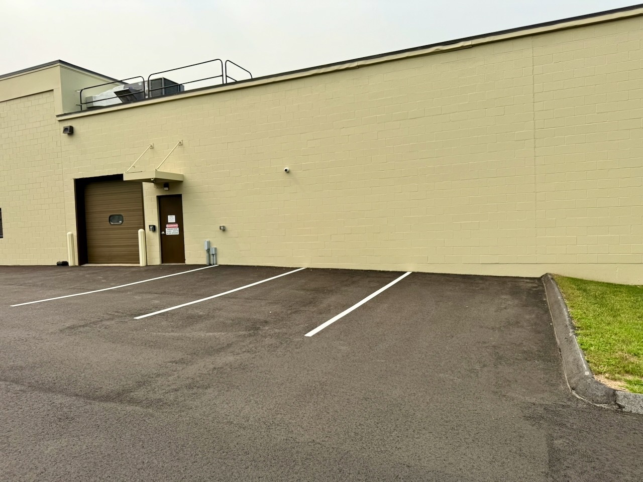 The rear of Building 1 at Southbury Self Storage with a drive-in overhead door and newly striped parking