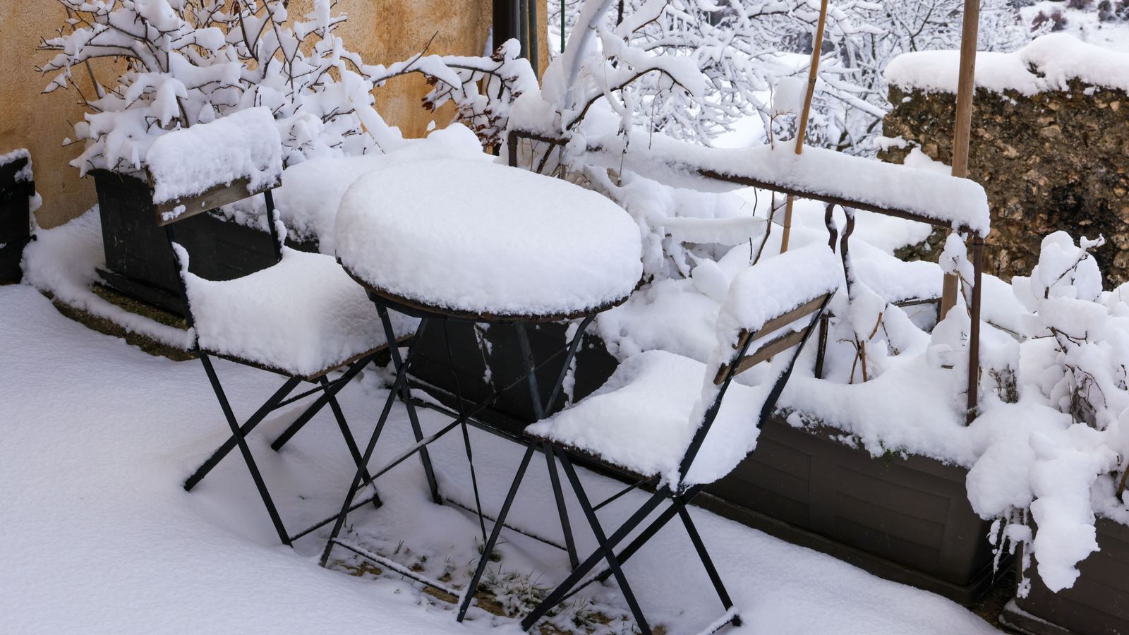 Snow-covered patio furniture before winter storage preparation in Northern Michigan