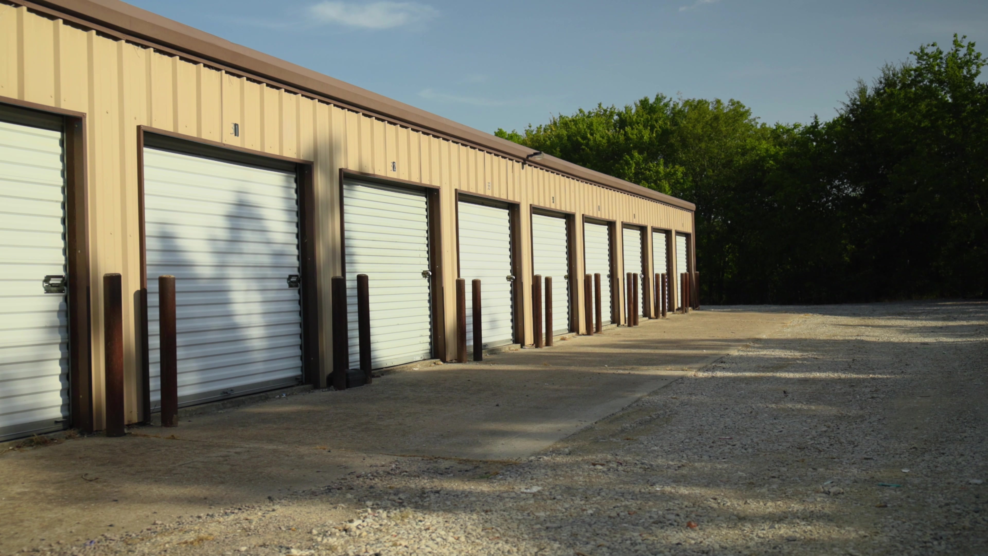 Ground level view of drive up self storage units with white roll up doors and wide gravel access lane at To the Point Storage, Point TX Ground level view of drive up self storage units with white roll up doors and wide gravel access lane at To the Point Storage, Point TX