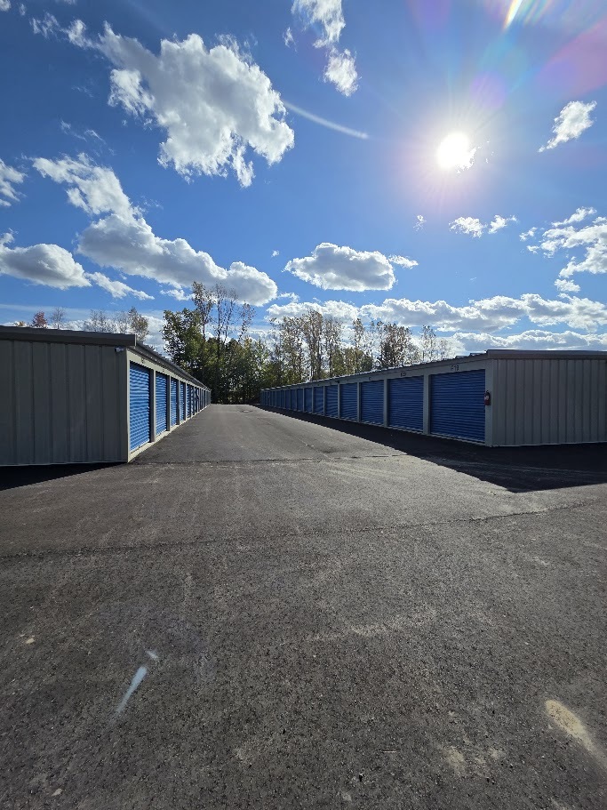 Paved drive aisle between rows of blue-door storage buildings at Handy Storage.