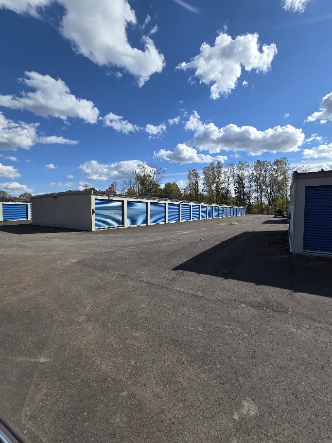 Long row of blue storage doors beside a paved drive at Handy Storage.