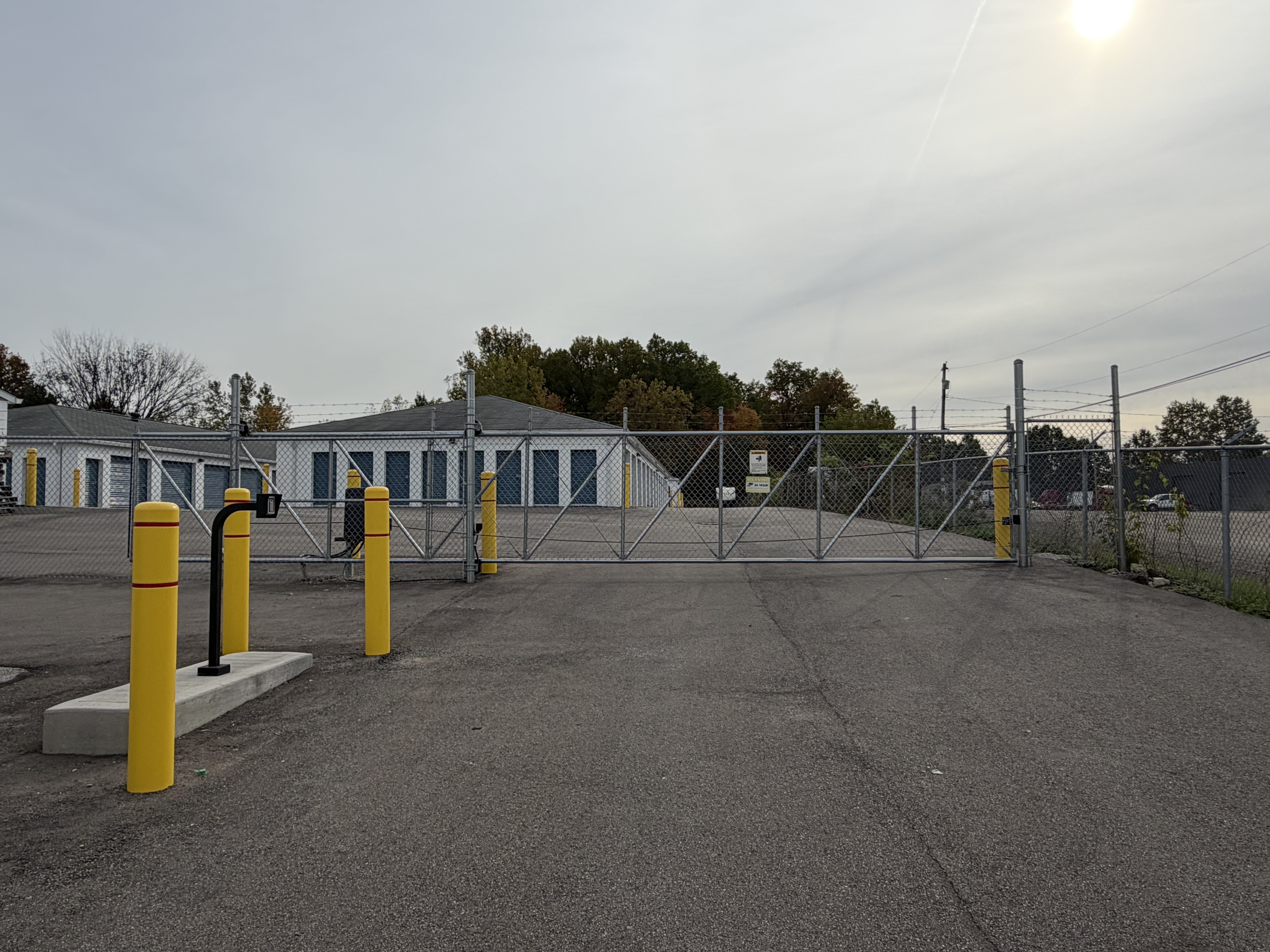 Gated Entrance to Blue Wave Storage, with security fencing, Key-Pad access equipment, and yellow safety bollards.