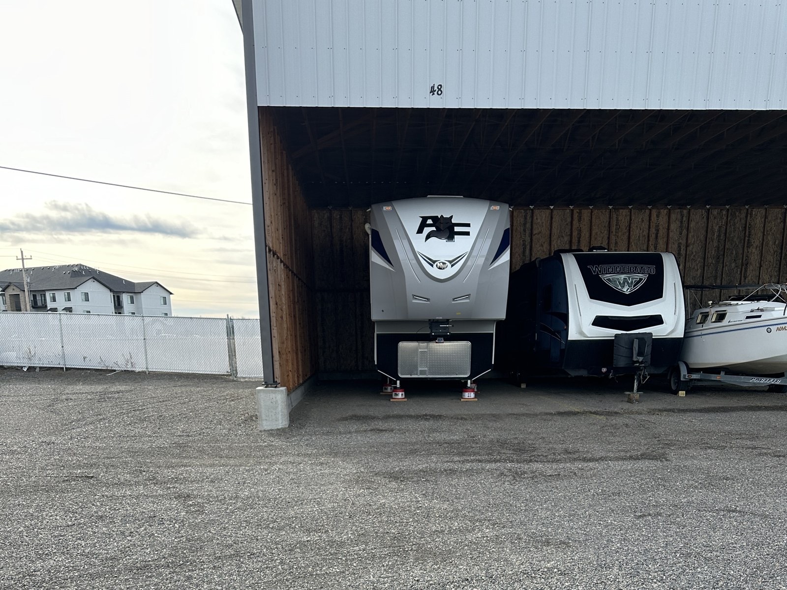 Fifth wheel, travel trailer and boat stored in covered spaces at Elite Storage in Rexburg, Idaho