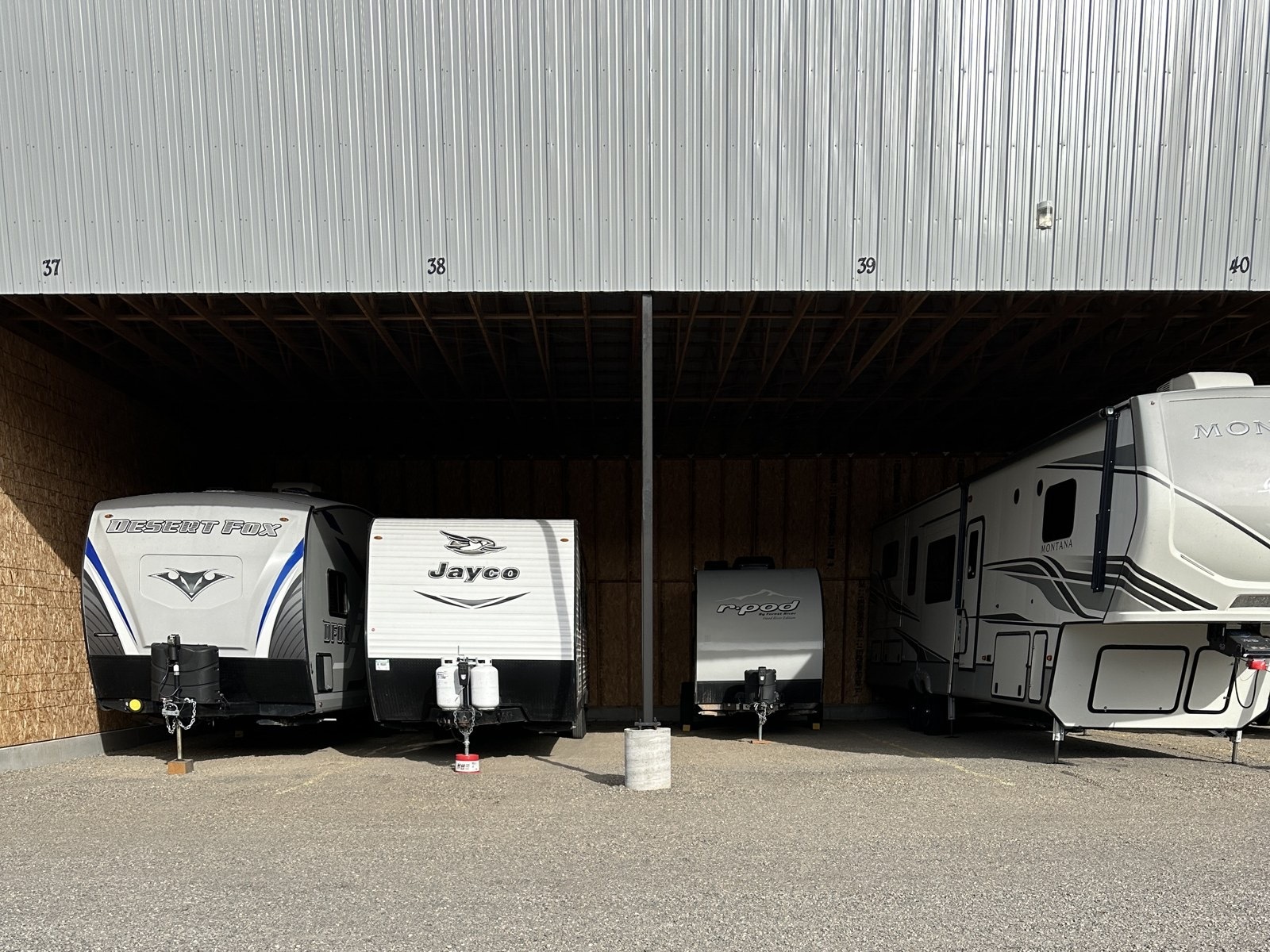 Travel trailers and a fifth wheel in numbered covered storage spaces at Elite Storage in Rexburg, Idaho