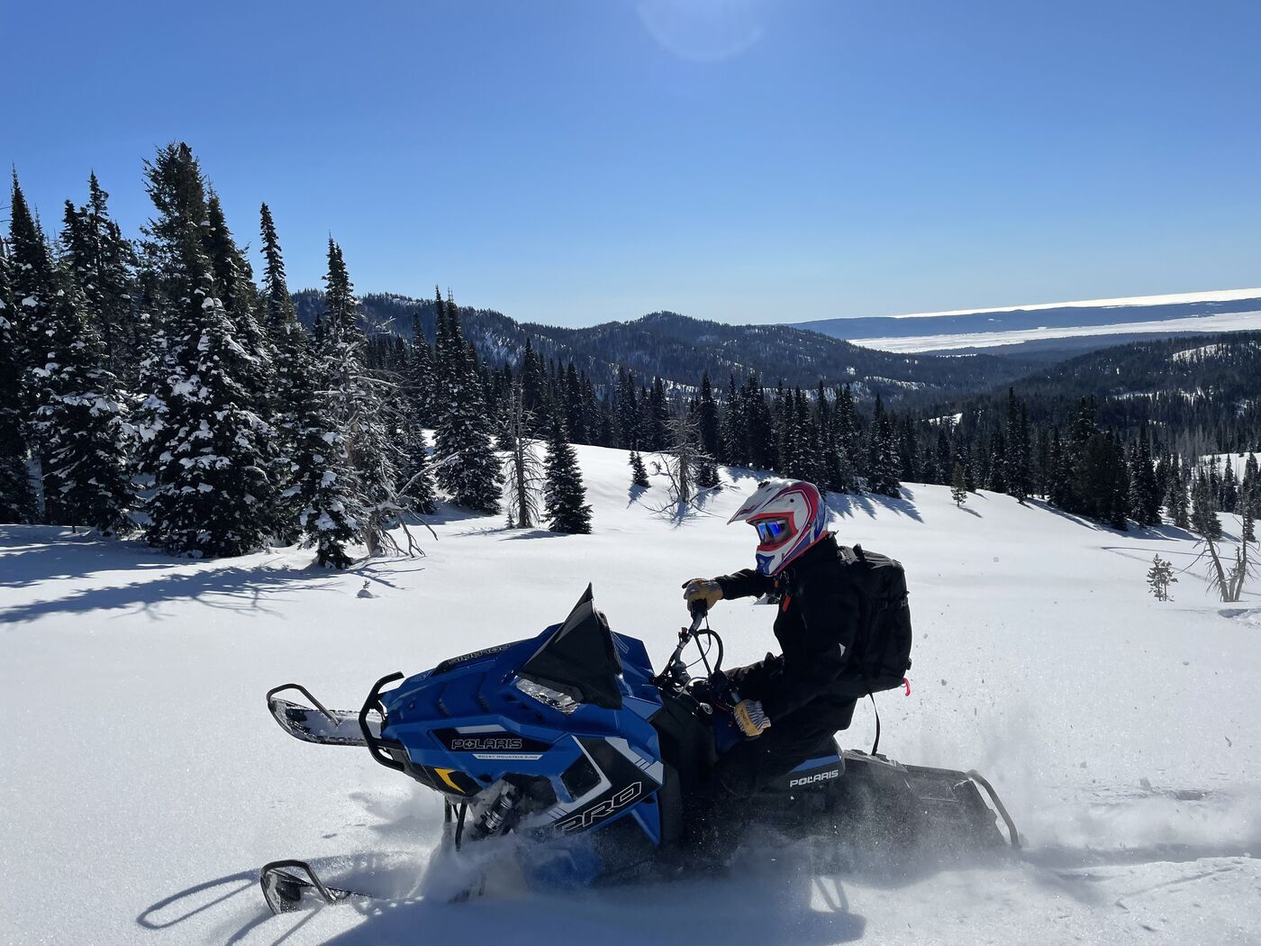Snowmobile rider in deep powder in Island Park Snowmobile rider in deep powder with mountain views in Island Park, Idaho