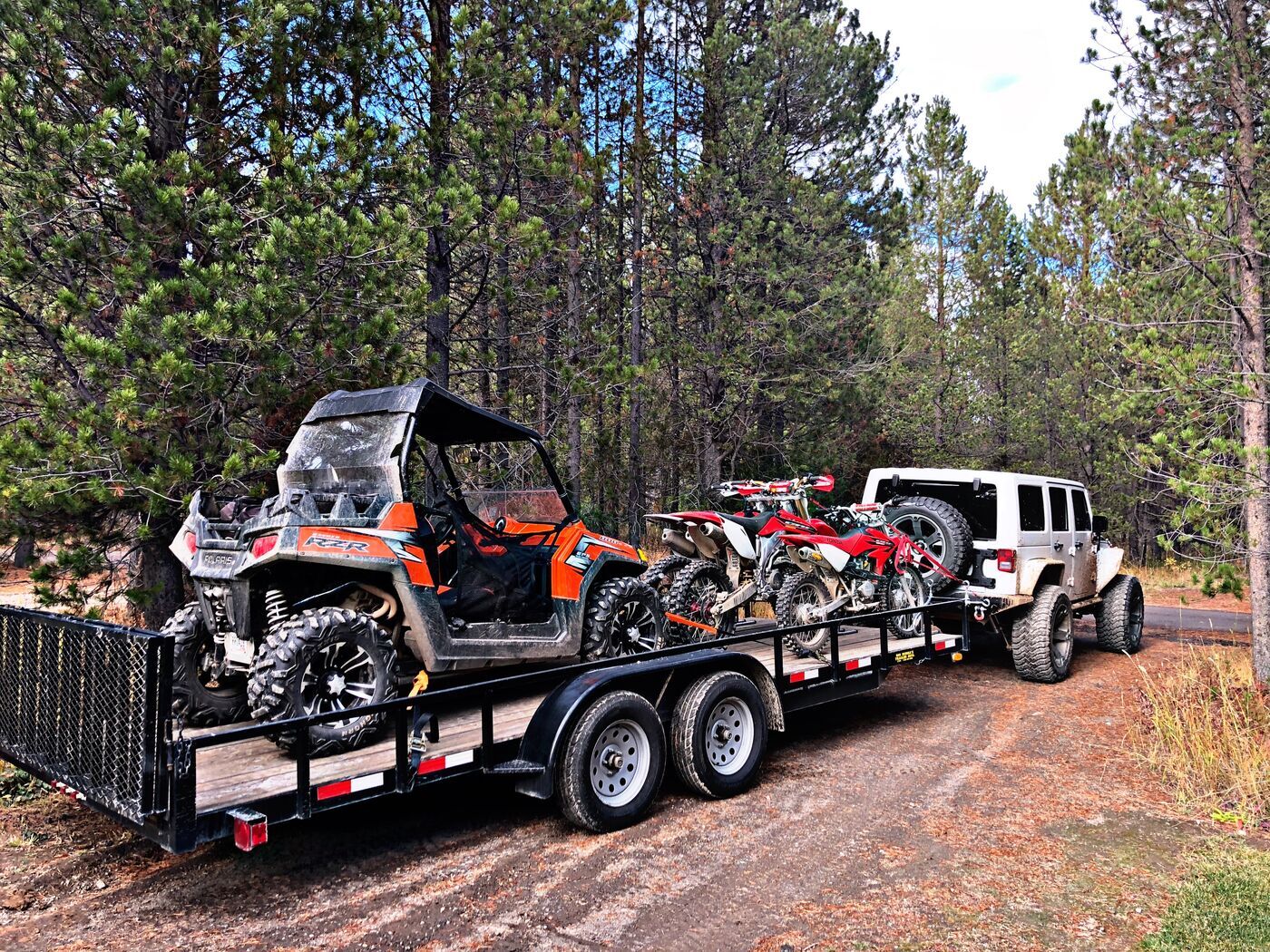 Side-by-side and dirt bikes loaded on a trailer Side-by-side and dirt bikes loaded on a trailer behind a Jeep in Island Park, Idaho