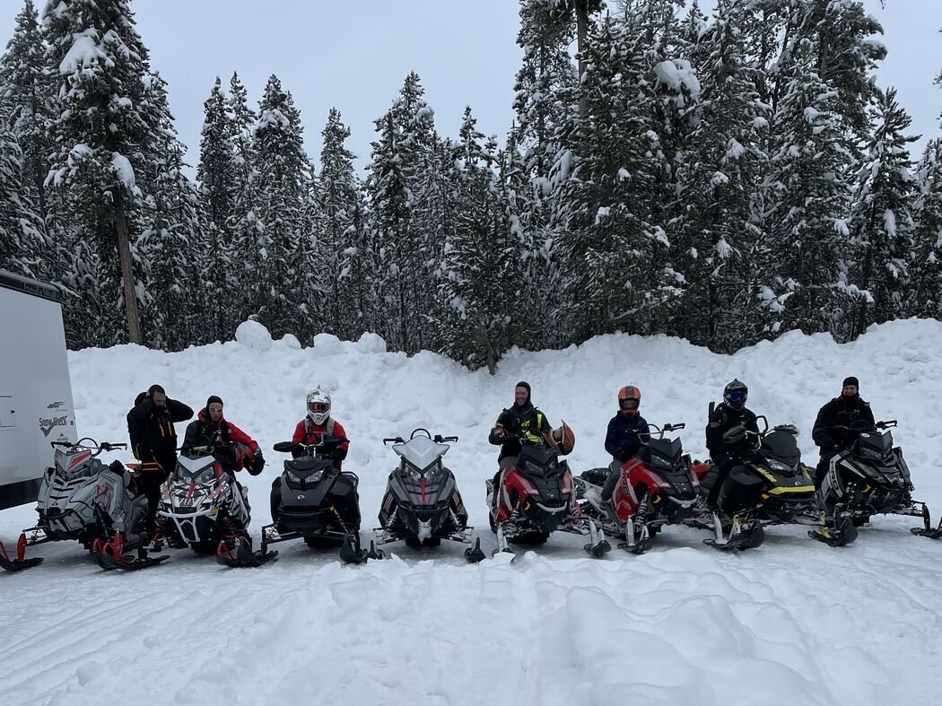 Snowmobiles lined up on a snowy trail Group of snowmobiles with riders on a snowy trail in Island Park, Idaho