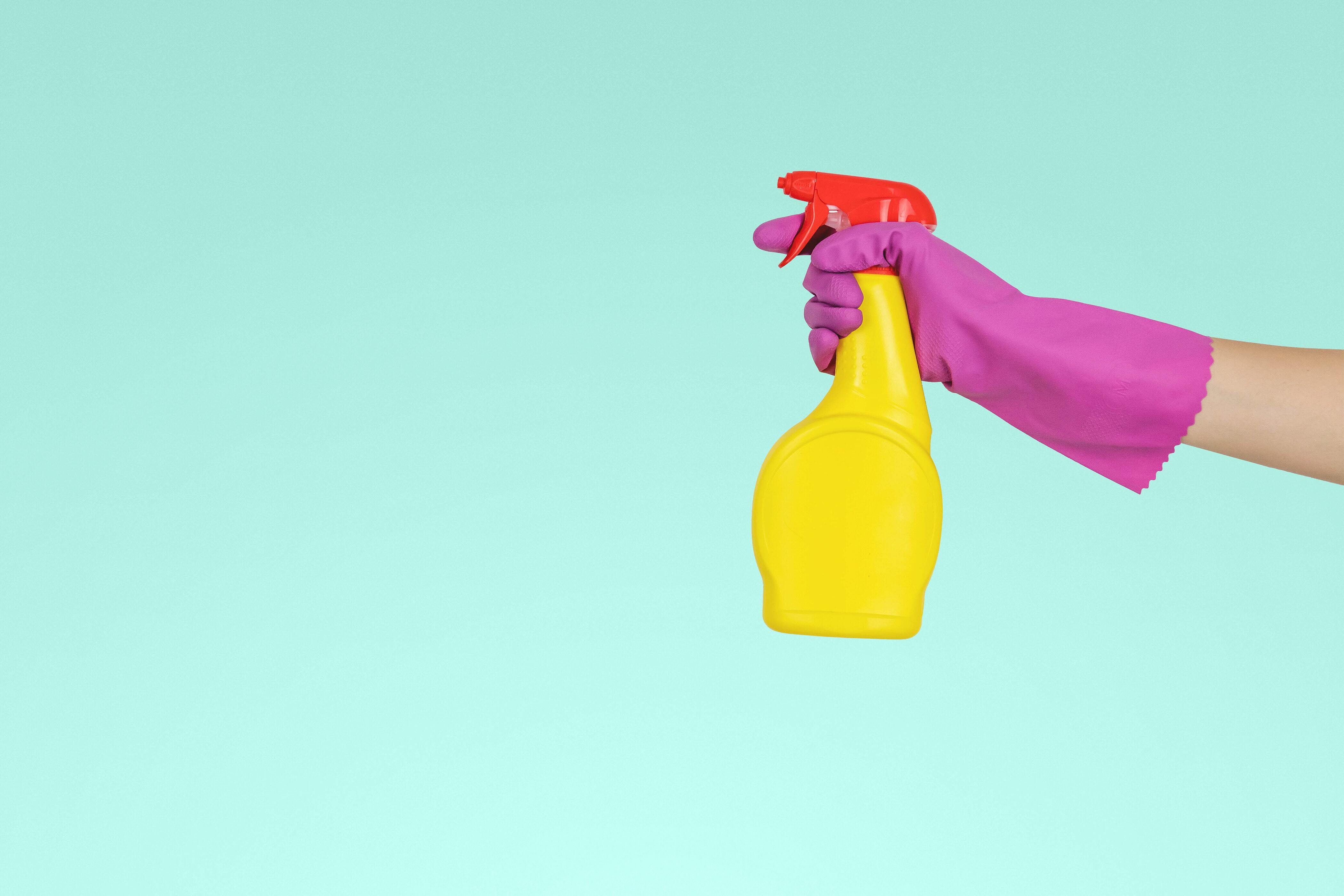 A yellow spray bottle in the grip of a hand